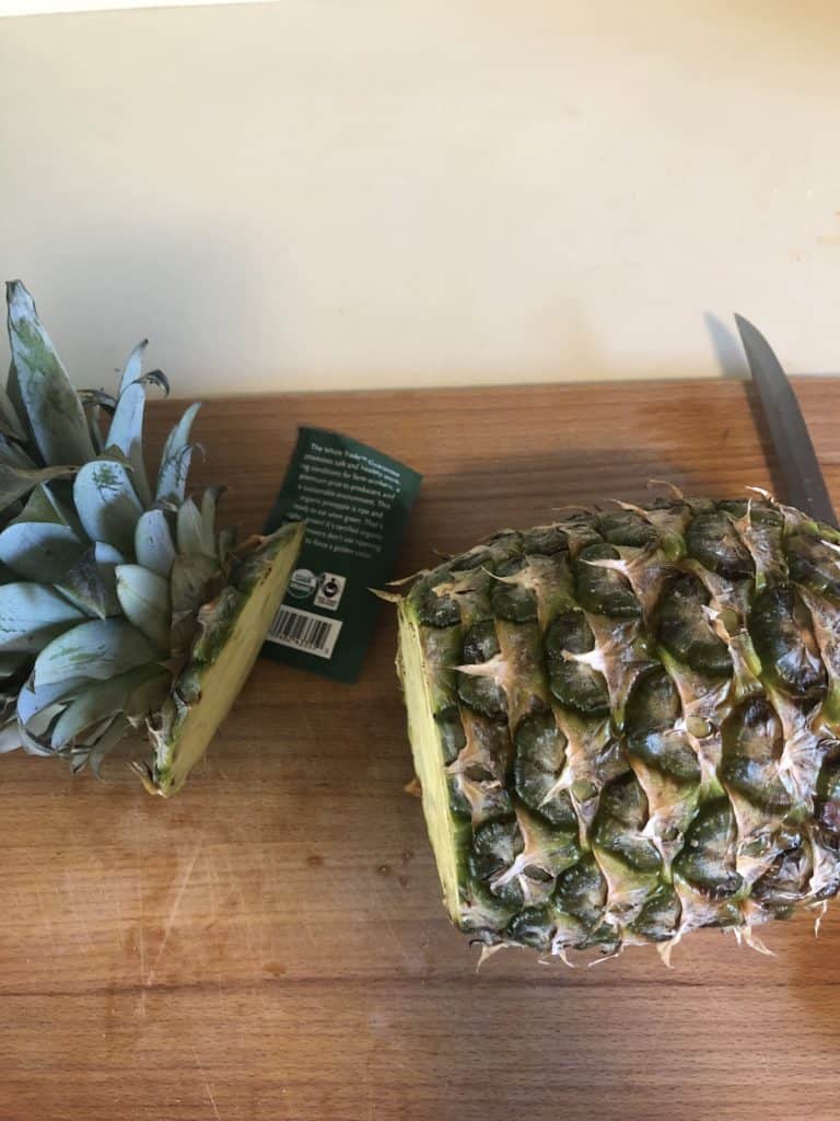 Slicing the top off of the pineapple.