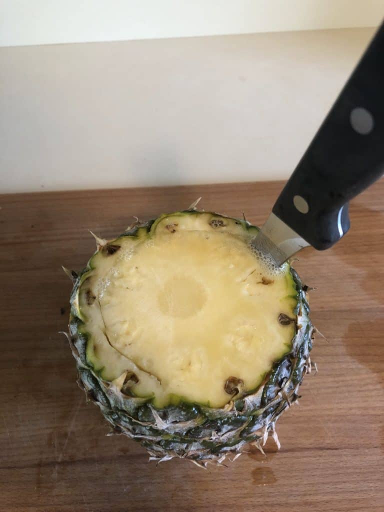 Cutting around the edge of the pineapple inside