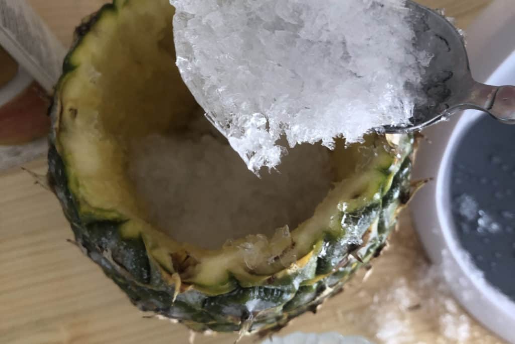 Spooning ice into the pineapple.